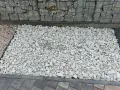 Biały grys na podjeździe obok gabionów i kostki brukowej.