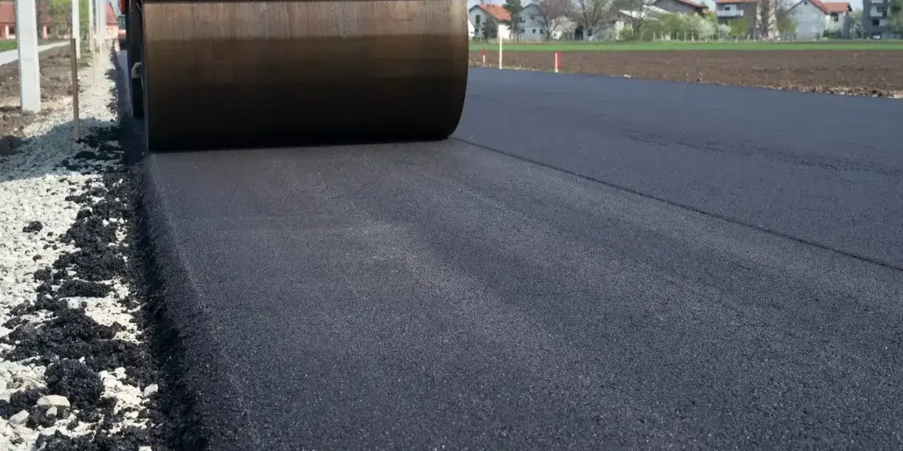Walec drogowy ubija świeży asfalt. Zastanawiasz się, ile kosztuje asfalt na podjazd?