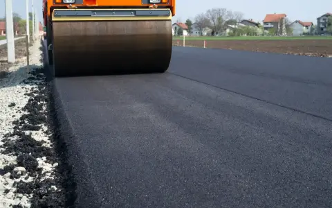 Walec drogowy ubija świeży asfalt. Zastanawiasz się, ile kosztuje asfalt na podjazd?