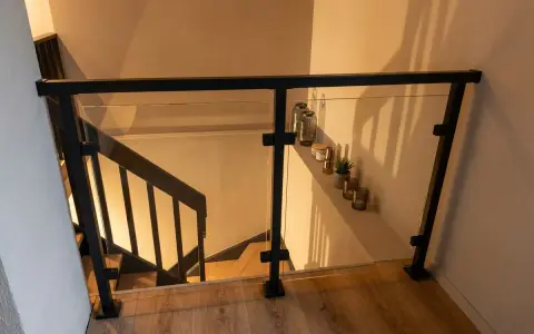 Nowoczesna balustrada ze szkła i czarnego profilu, idealna do schodów. Pokazuje, jak zrobić balustradę z profila.