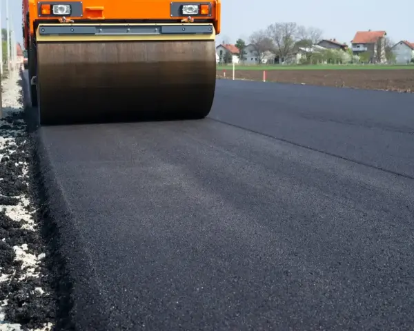 Walec drogowy ubija świeży asfalt. Zastanawiasz się, ile kosztuje asfalt na podjazd?