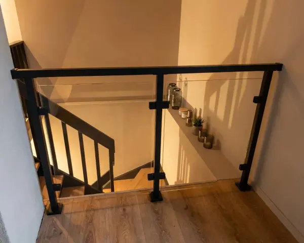 Nowoczesna balustrada ze szkła i czarnego profilu, idealna do schodów. Pokazuje, jak zrobić balustradę z profila.